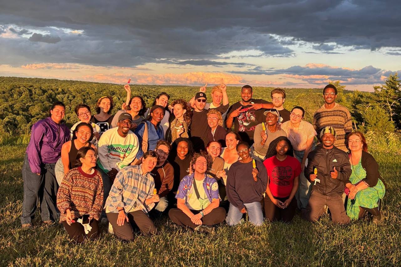 UCraft participants standing together on a hillside at sunset, forest and a wide sky behind them