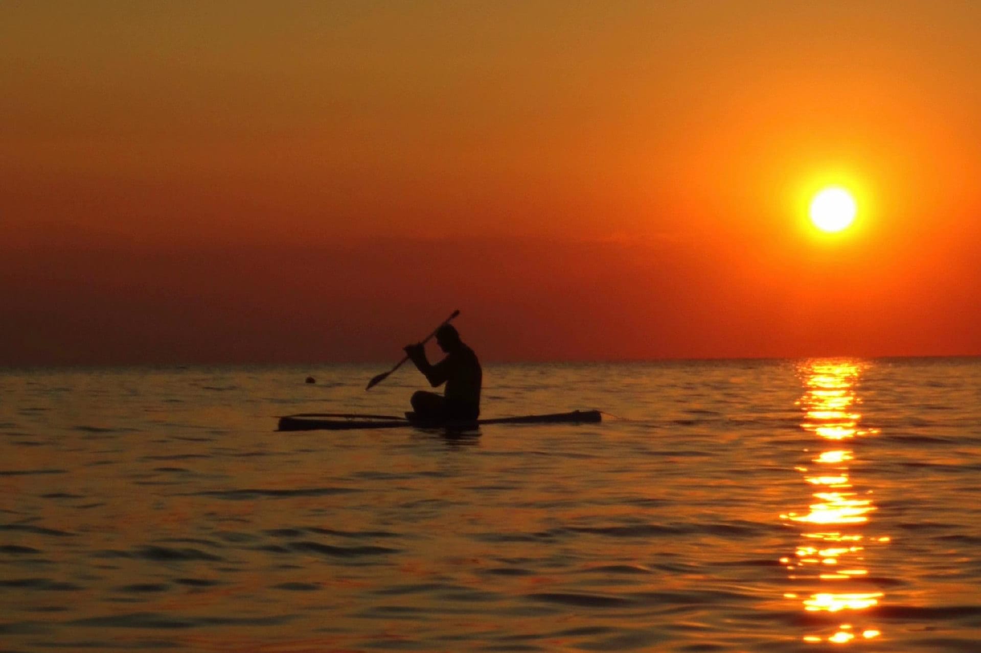 Sunset over Tudakul, a paddleboarder silhouetted against the water